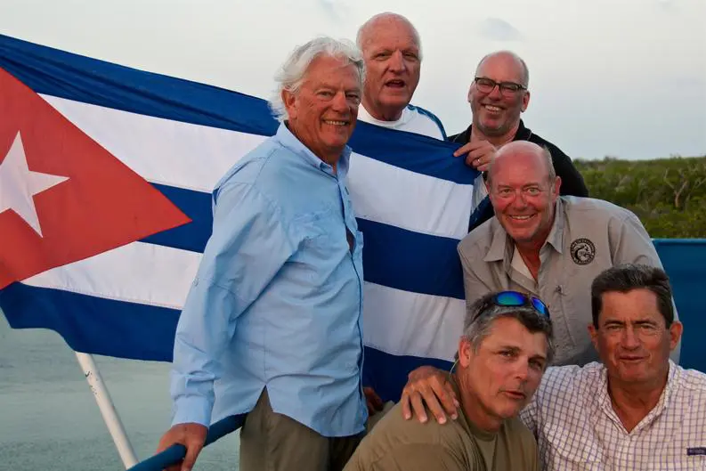 34d6db5abb0e18db3bfb69054f2cf7e7 Six men posing in front of a Cuban flag, outdoors.